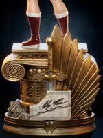 Gold Wonder Woman statue trophy with winged emblem, marble signature plaque, and red-booted legs standing on a pedestal.