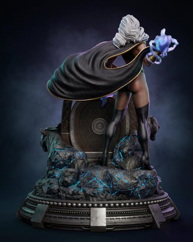 Detailed statue of a caped female hero with a glowing blue energy hand, standing on a rocky pedestal with a futuristic circular base at the back.