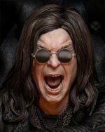 Person with long dark hair and round sunglasses screaming with mouth wide open, wearing a black leather jacket and chain necklace.