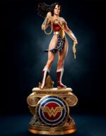 Statue of Wonder Woman in red, gold, and blue armor, wielding her golden lasso atop a decorative gold pedestal.