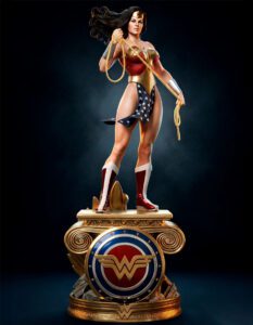 Statue of Wonder Woman in red, gold, and blue armor, wielding her golden lasso atop a decorative gold pedestal.