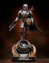 Collectible statue of the Mandalorian standing with Grogu in a pouch on his chest, atop a round display base against a dark background.